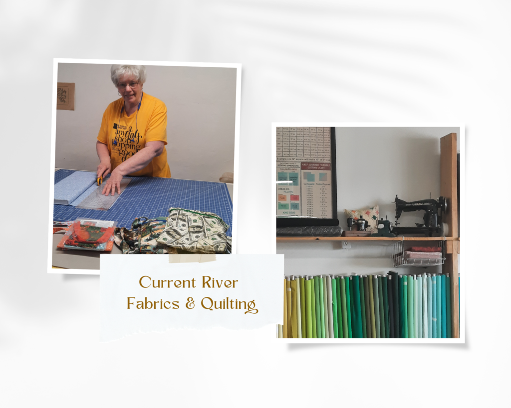 Current River Fabrics and Quilting owner cutting fabric and an old sewing machine over a shelf of fabric bolts.